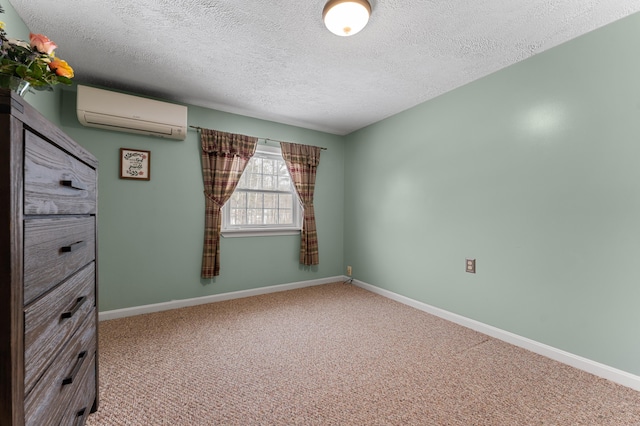 carpeted empty room with baseboards, a textured ceiling, and a wall unit AC