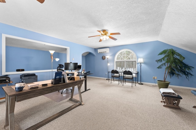 office area with a wall unit AC, vaulted ceiling, carpet flooring, arched walkways, and a ceiling fan