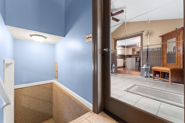 corridor with lofted ceiling, baseboards, and tile patterned floors