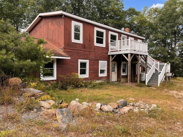 rear view of house with a deck, stairs, and a chimney