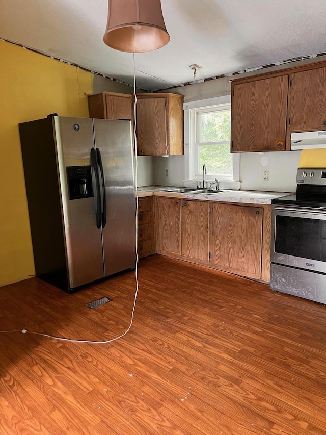 kitchen with visible vents, under cabinet range hood, a sink, wood finished floors, and appliances with stainless steel finishes