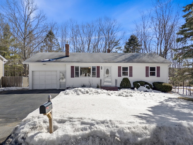 single story home featuring aphalt driveway, an attached garage, a chimney, and fence