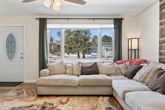 living room featuring a textured ceiling, wood finished floors, baseboards, and ceiling fan