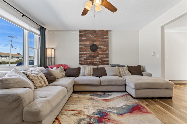 living room featuring a baseboard radiator, a textured ceiling, wood finished floors, and a ceiling fan