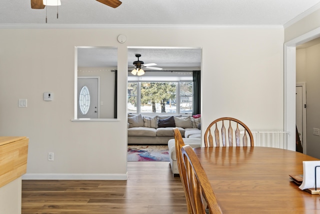 dining area with ceiling fan, baseboards, ornamental molding, wood finished floors, and a textured ceiling