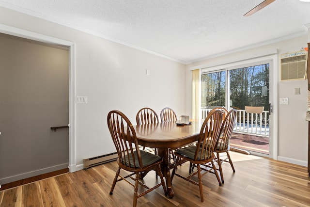 dining space featuring crown molding, baseboards, baseboard heating, wood finished floors, and a textured ceiling