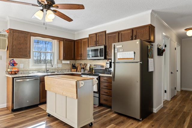 kitchen with dark wood-style floors, ornamental molding, light countertops, appliances with stainless steel finishes, and tasteful backsplash