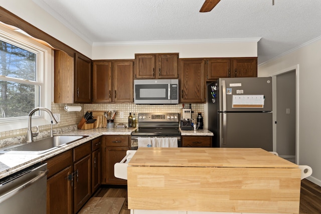 kitchen featuring dark wood-style floors, wooden counters, a kitchen island, a sink, and appliances with stainless steel finishes