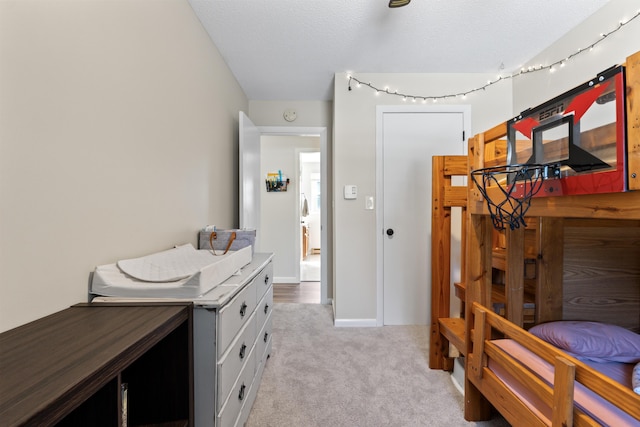 bedroom with light colored carpet, baseboards, and a textured ceiling