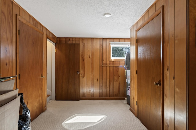 corridor featuring carpet flooring, wood walls, and a textured ceiling