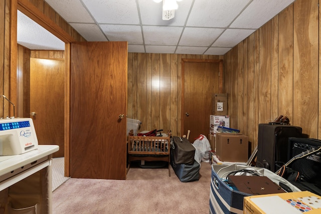 bedroom featuring a drop ceiling, carpet floors, and wood walls