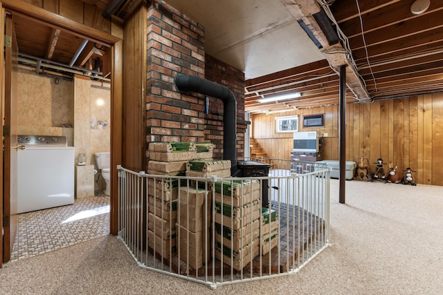 basement featuring wooden walls, washer / dryer, and carpet floors