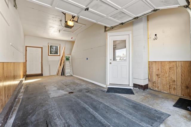 garage featuring wooden walls, a garage door opener, and wainscoting