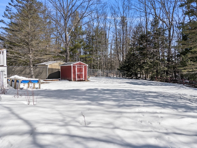 yard covered in snow featuring an outdoor structure, a storage unit, and fence