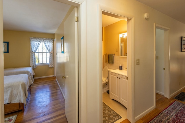 bedroom featuring light wood-style flooring, visible vents, baseboards, and connected bathroom