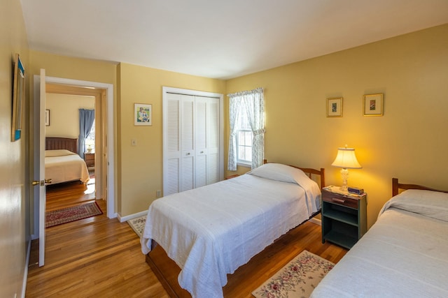 bedroom with a closet, baseboards, and wood finished floors