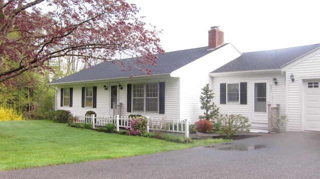 ranch-style house featuring a shingled roof, a front yard, a garage, and a chimney