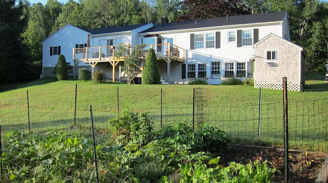 rear view of house featuring a wooden deck, a lawn, fence, and a chimney