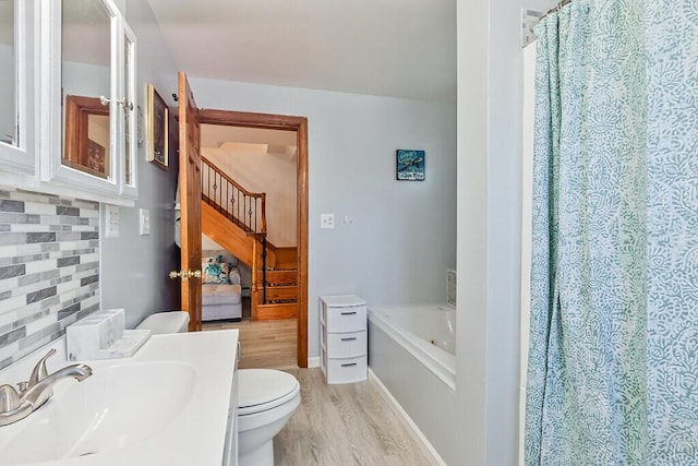 full bath with wood finished floors, vanity, toilet, decorative backsplash, and a bath