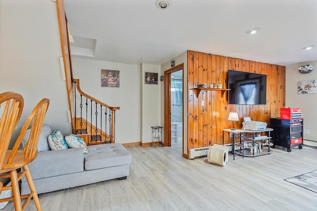 living area with stairway, wood finished floors, wood walls, a baseboard radiator, and baseboards