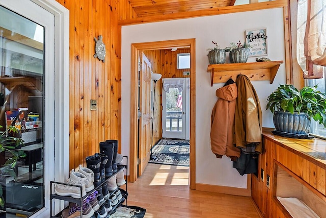 foyer entrance featuring light wood-style floors, baseboards, and wooden walls