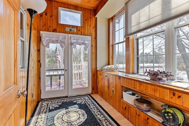 doorway to outside with wood walls