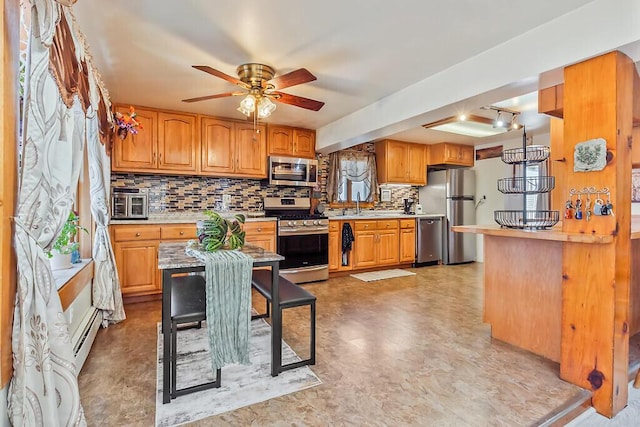 kitchen featuring light countertops, decorative backsplash, a ceiling fan, appliances with stainless steel finishes, and baseboard heating