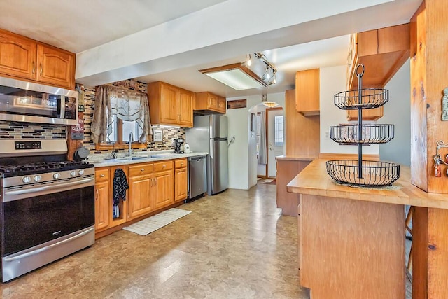 kitchen with decorative backsplash, brown cabinets, appliances with stainless steel finishes, arched walkways, and a sink