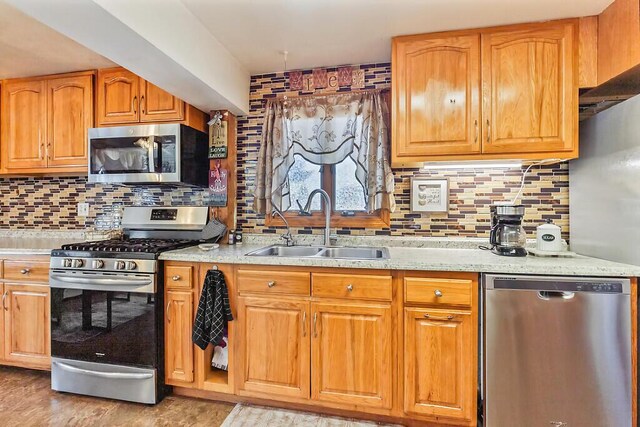 kitchen with decorative backsplash, a sink, stainless steel appliances, and light stone counters