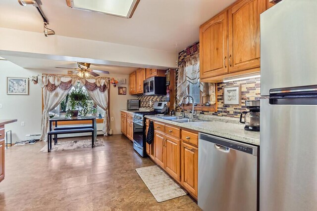 kitchen with light stone countertops, a ceiling fan, appliances with stainless steel finishes, a sink, and backsplash