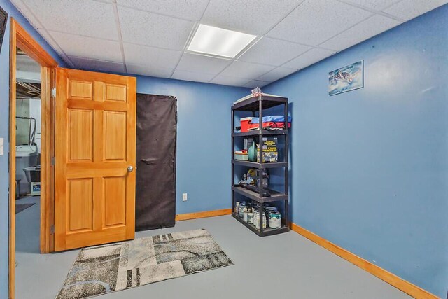 bedroom with baseboards, concrete flooring, and a paneled ceiling