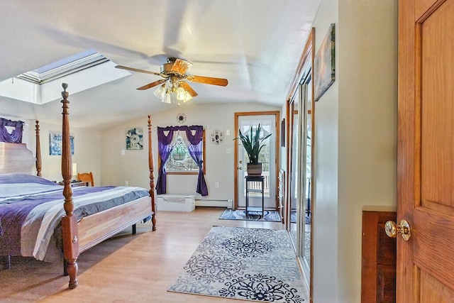 bedroom featuring a baseboard radiator, light wood-style flooring, and lofted ceiling with skylight