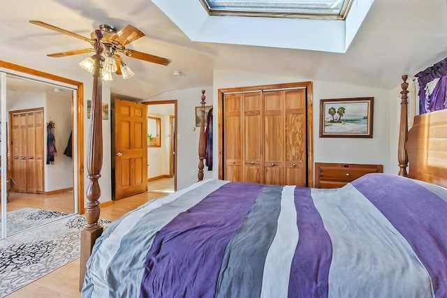 bedroom with light wood-style flooring, baseboards, vaulted ceiling with skylight, and ceiling fan