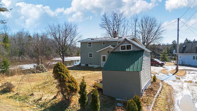 view of property exterior with metal roof and a chimney