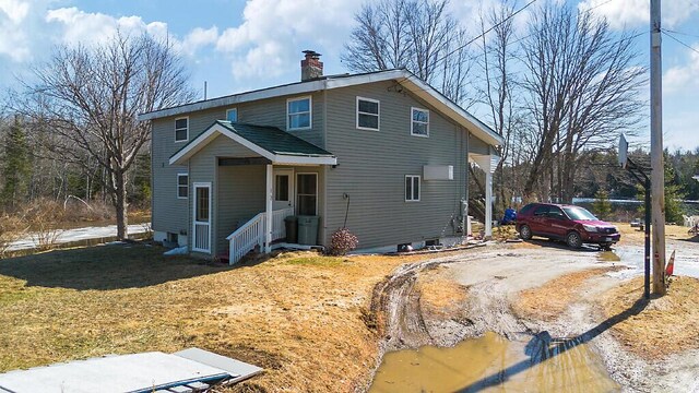 traditional-style house featuring a chimney and dirt driveway