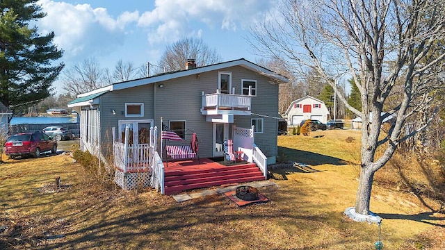 rear view of property featuring a balcony, a lawn, a water view, and a chimney