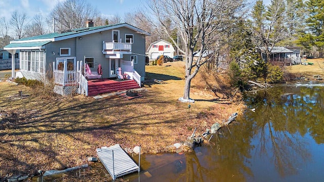 back of house with a balcony, a chimney, and a water view