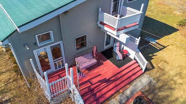 exterior space featuring a balcony, a deck, and a lawn