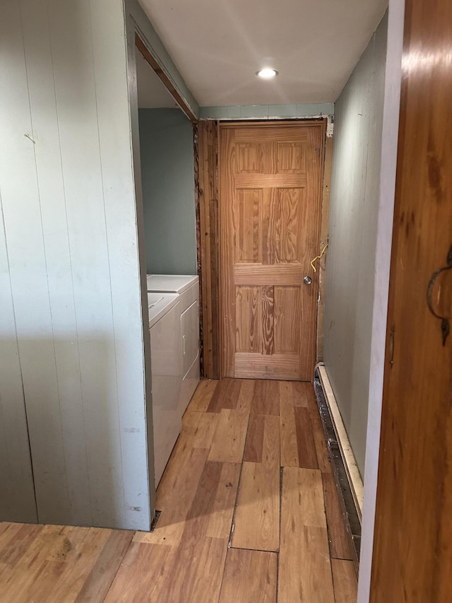 hall with a baseboard heating unit, light wood finished floors, and washer and clothes dryer