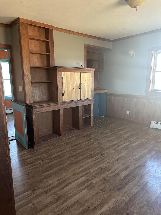 interior space featuring a wainscoted wall, dark wood-style flooring, and a baseboard heating unit