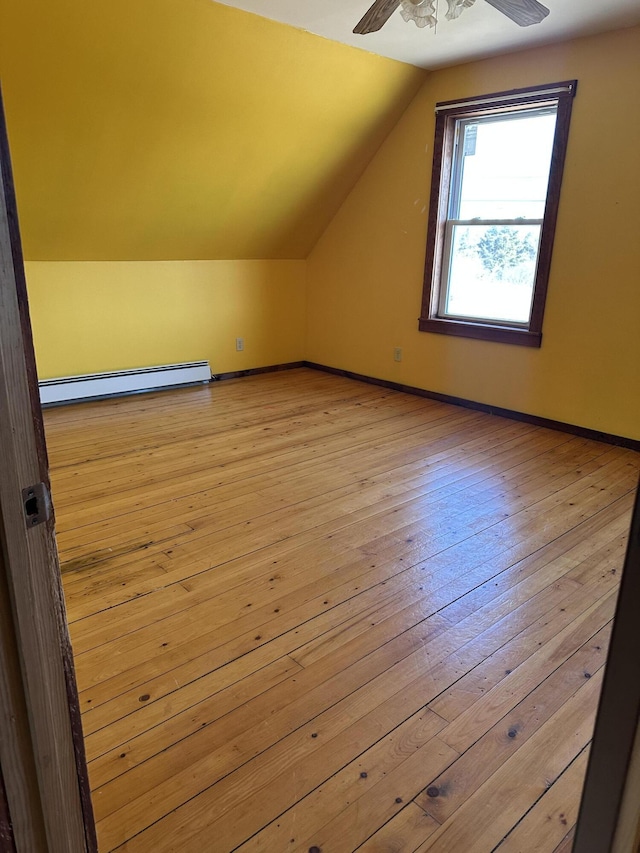 bonus room with baseboards, light wood finished floors, ceiling fan, vaulted ceiling, and a baseboard heating unit