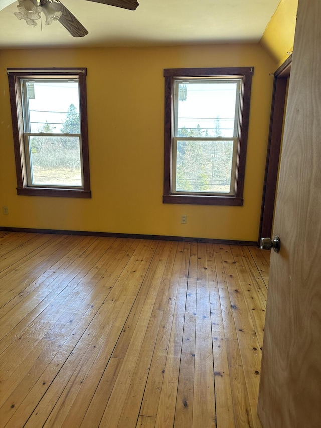 empty room with light wood-type flooring, baseboards, a healthy amount of sunlight, and ceiling fan