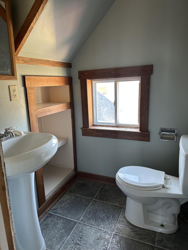 bathroom with lofted ceiling, toilet, and baseboards