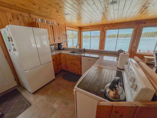 kitchen with white appliances, wood ceiling, a water view, and a sink