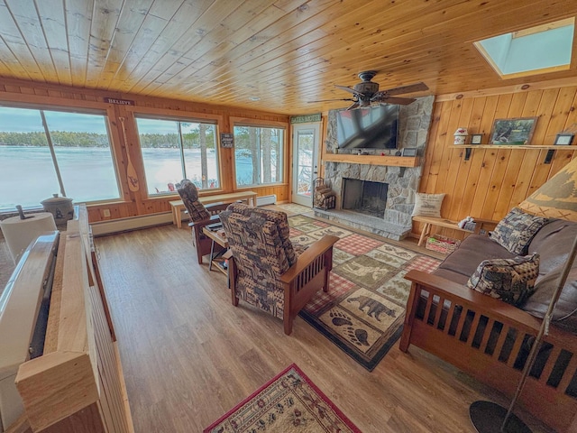 living room featuring wood finished floors, a skylight, a stone fireplace, wood walls, and wooden ceiling