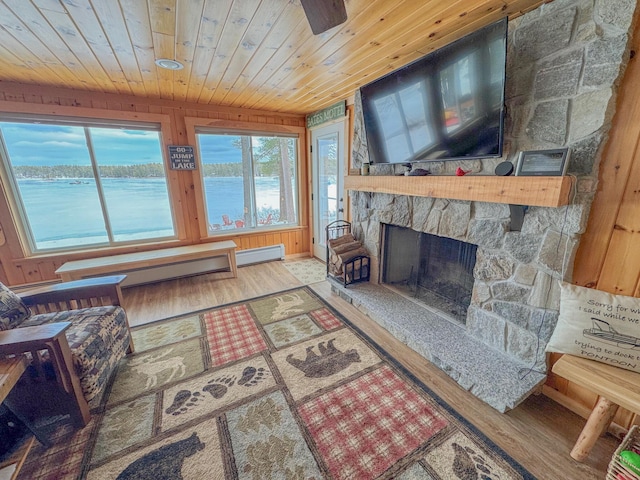 living room featuring wooden walls, wood finished floors, a baseboard radiator, a fireplace, and wood ceiling