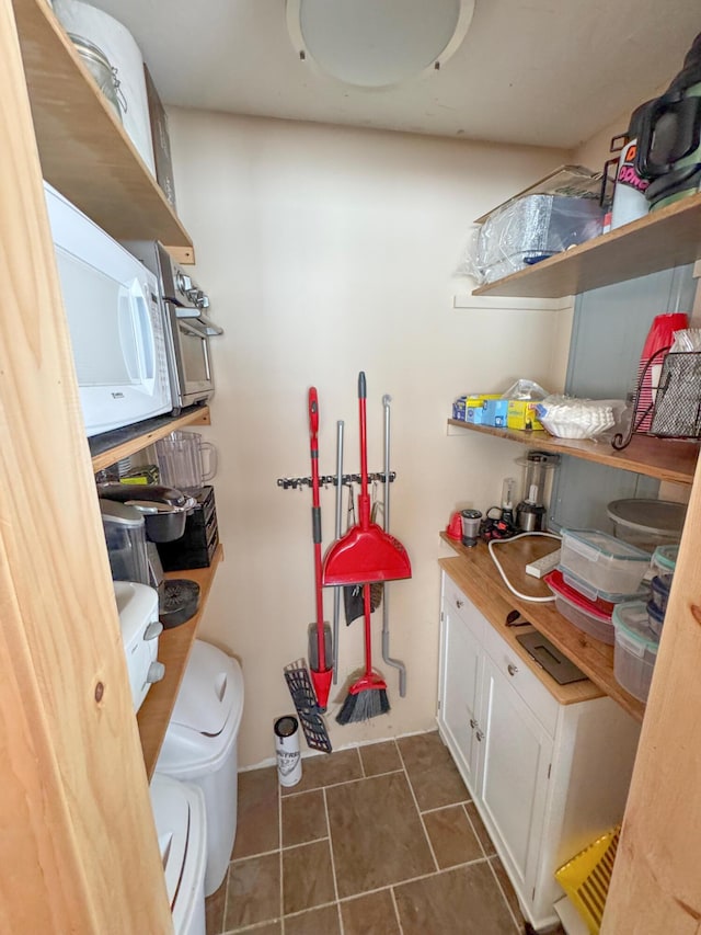 laundry area with cabinet space and dark tile patterned flooring