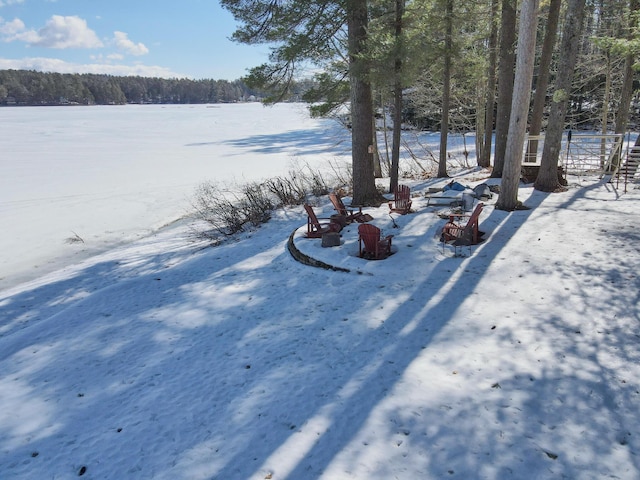 snowy yard with a view of trees and a fire pit