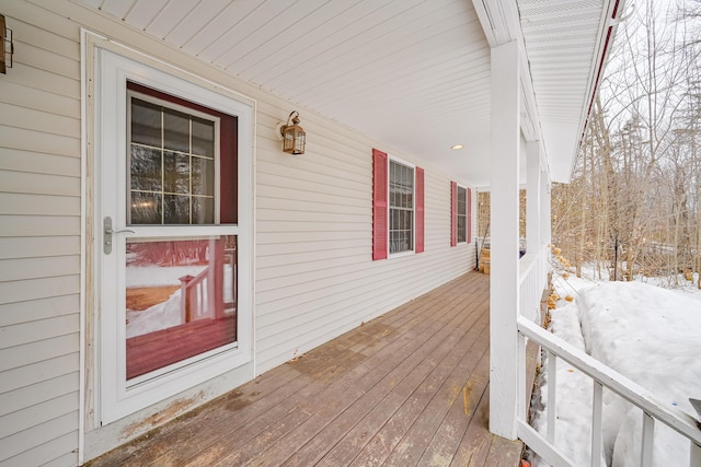 snow covered deck featuring covered porch