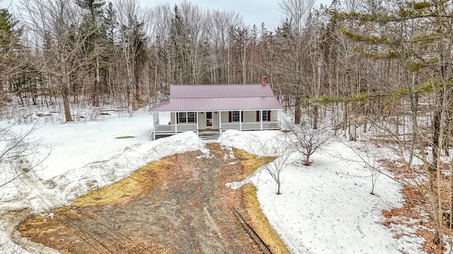 view of front facade featuring a porch, a forest view, and metal roof